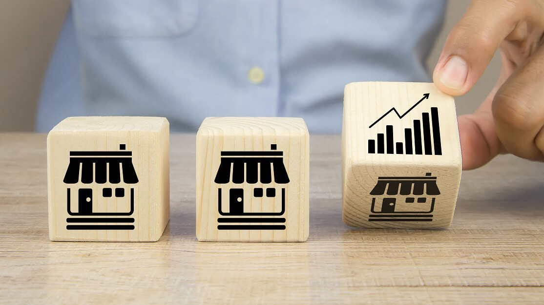 Cubos de madeira com desenhos de empresas representando as franquias, um tipo de investimento seguro e rentável