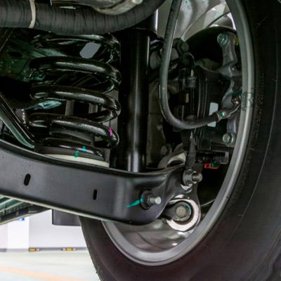 Técnico automotivo inspecionando amortecedor traseiro no elevador