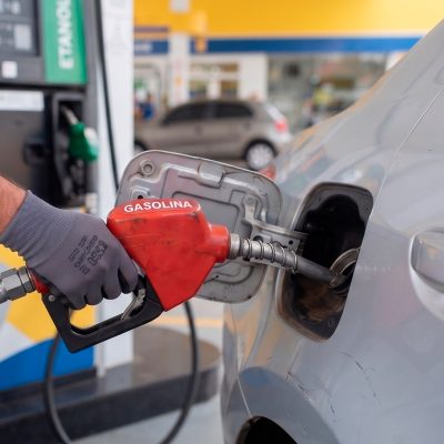 Mão abastecendo carro com bomba de gasolina — como economizar combustível com hábitos de direção e manutenção